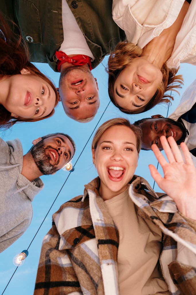 A diverse group of friends smiling into a camera outdoors, capturing a joyful moment.